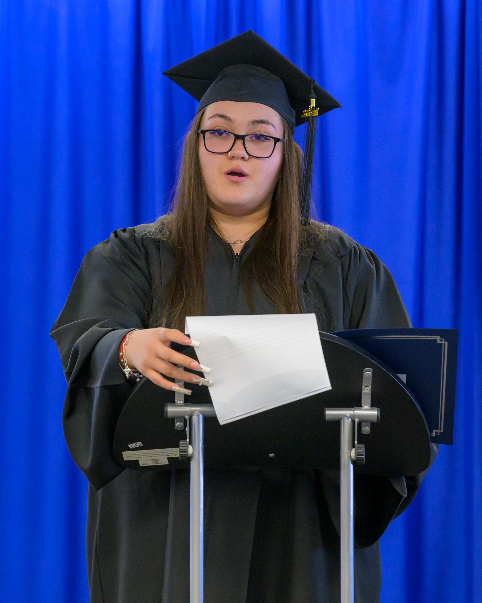 High school graduate stands at podium giving speech.