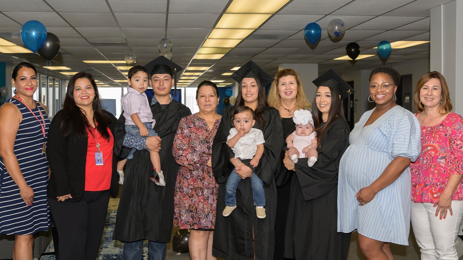 Graduates hold their babies with group of Ector Acceleration Academies staff members.