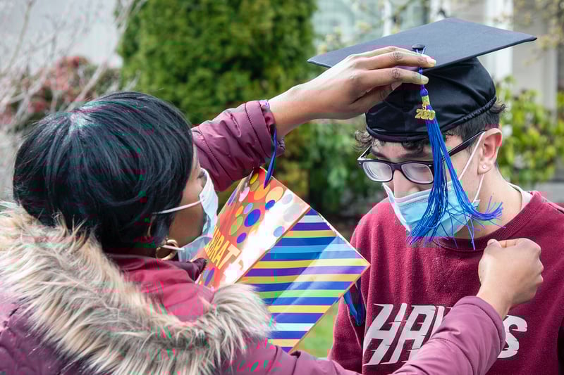 Student in mask has graduation cap adjusted