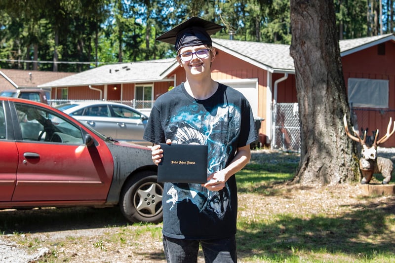 Bladen Wheaton holds his diploma outside of his house