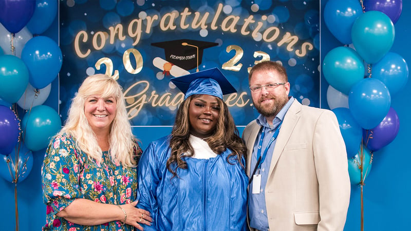 Kennede Thomas smiles at graduation with Acceleration Academies teachers and staff