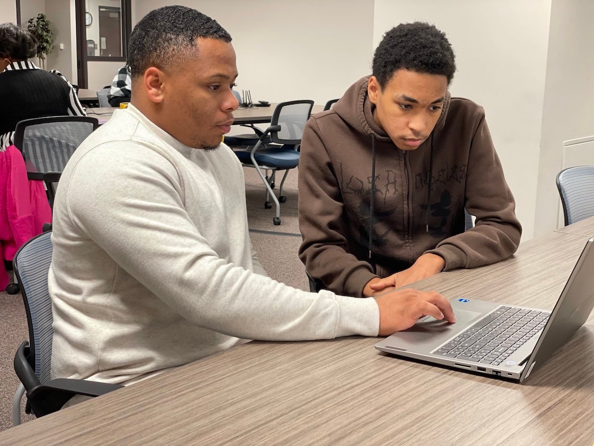 Student receives support from teacher by laptop