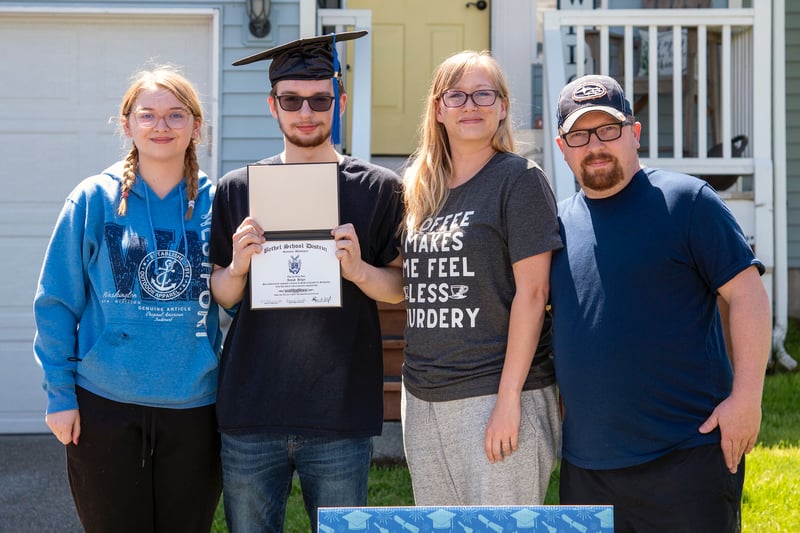 Joseph Bilger poses with family and diploma outside house