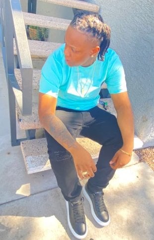High school student in blue t-shirt sits on steps outside of a building