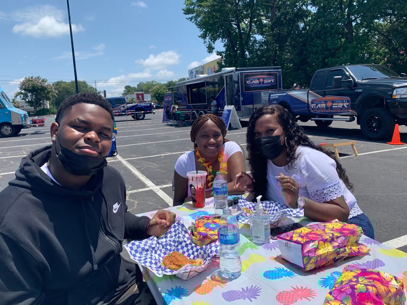Students sit at a table a party and eat