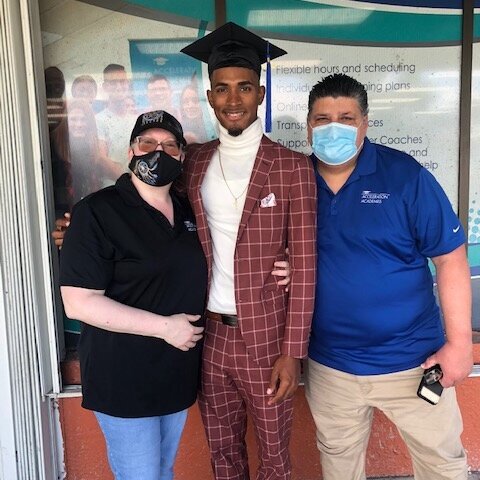 Graduate in suit poses with teachers