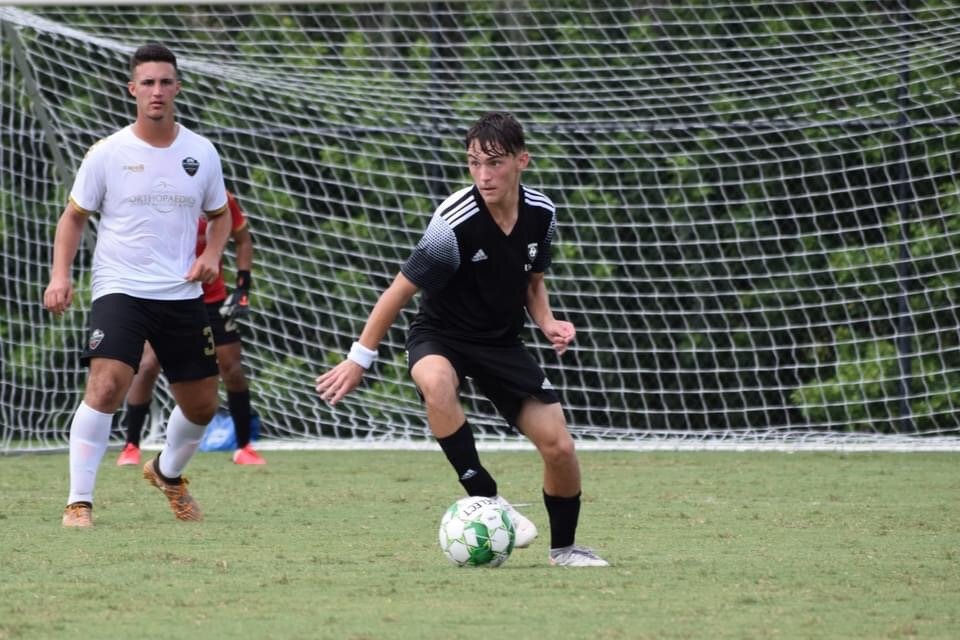 Teen in black jersey kicks soccer ball