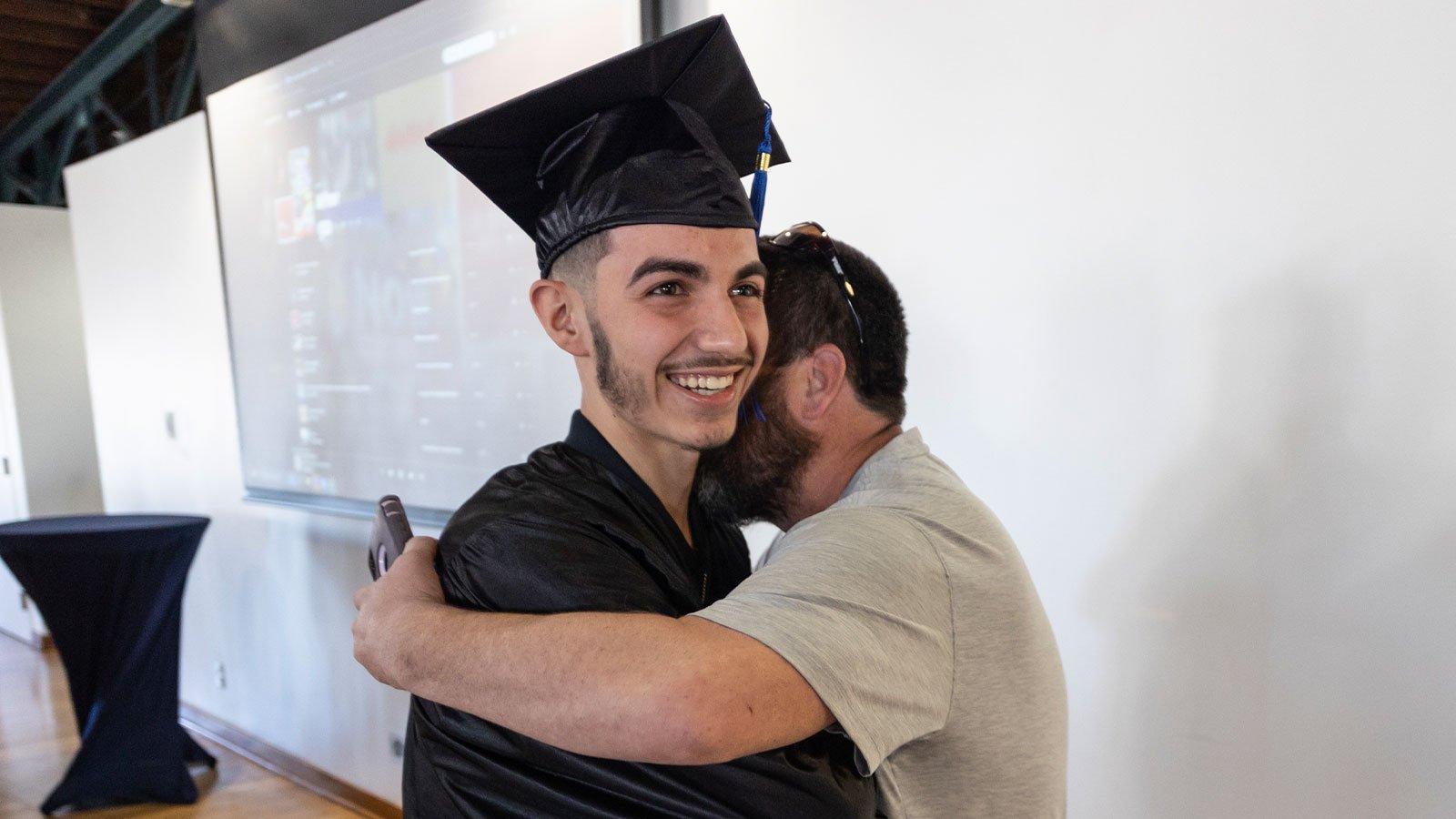Graduate hugs man.