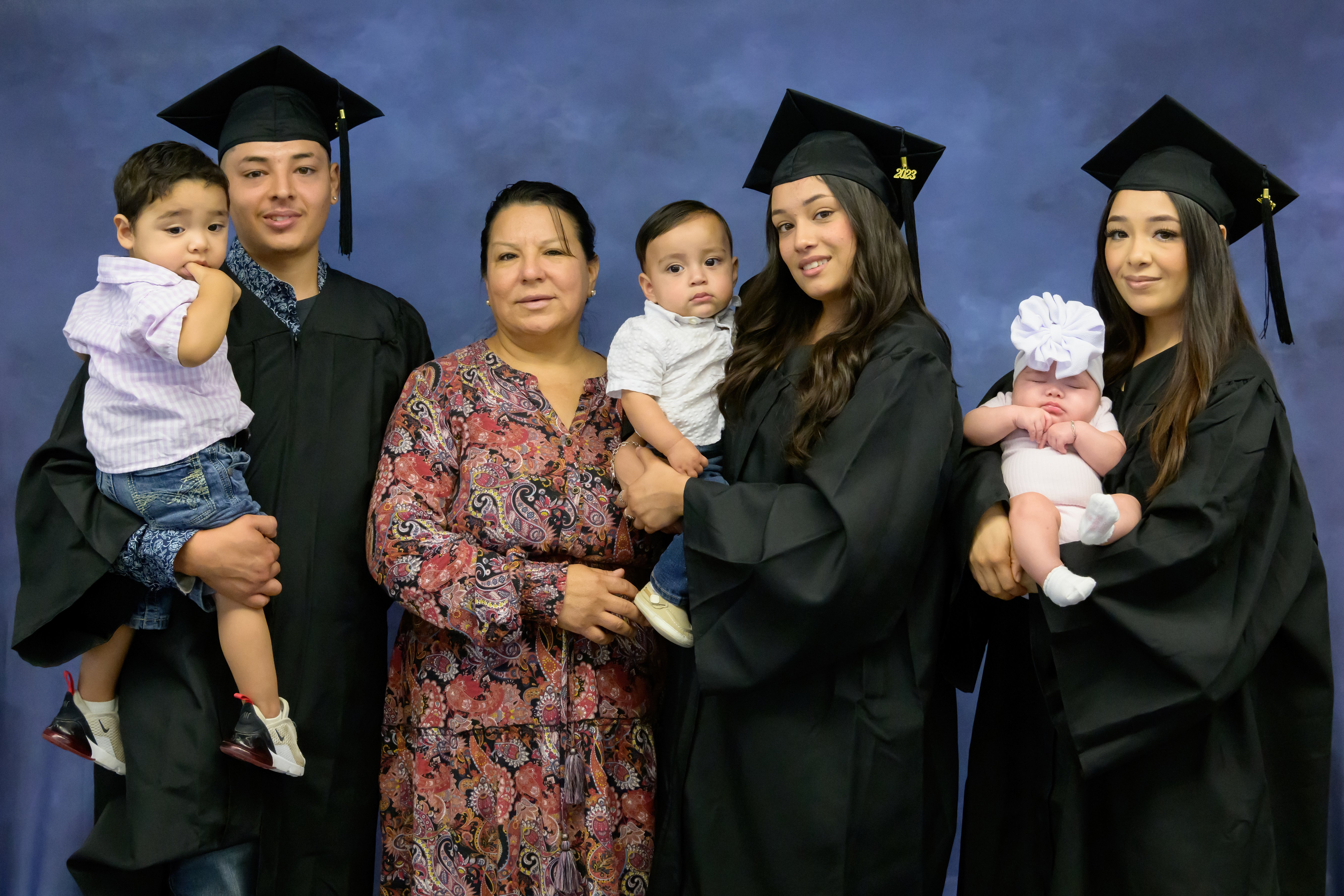 3 siblings pose with their mom and babies for graduation photo.