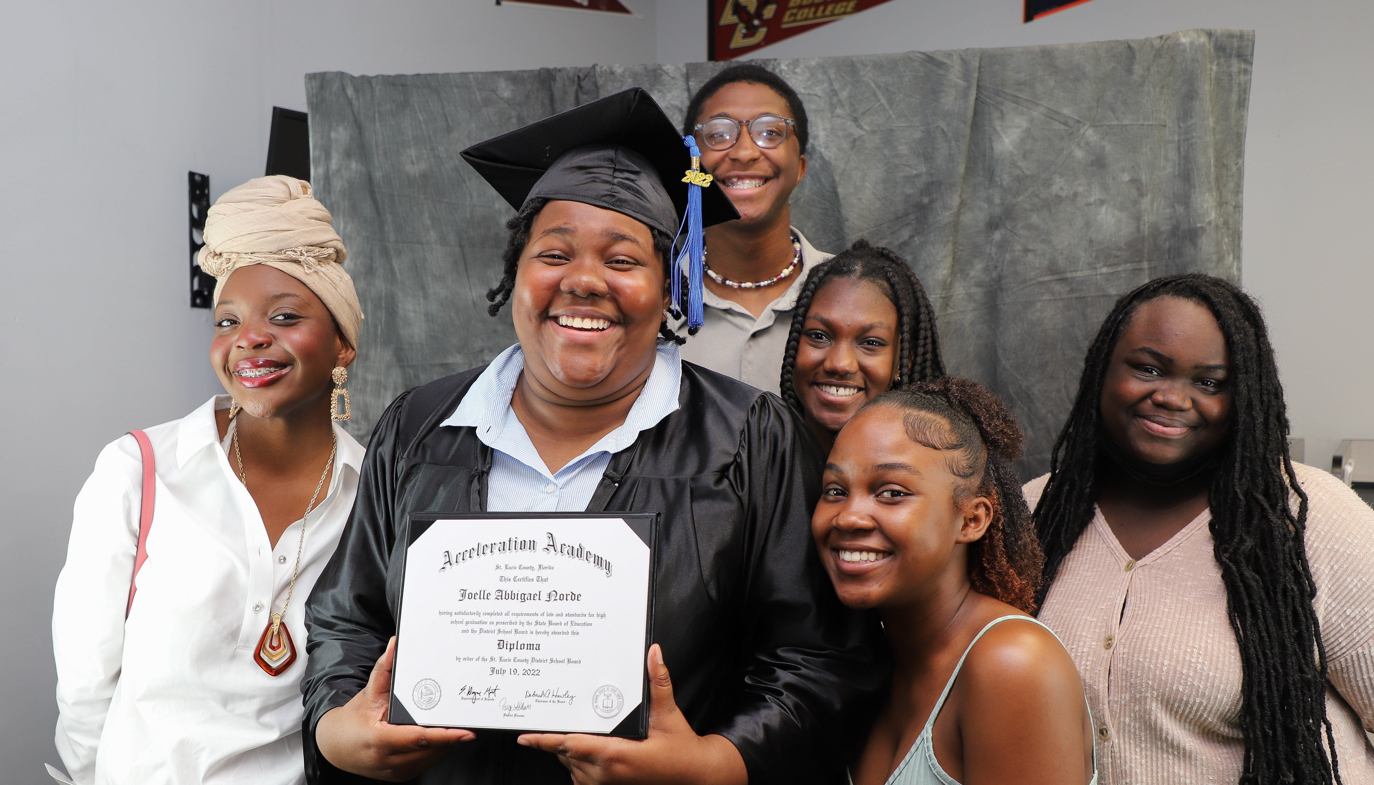 A student smiling with their diploma surrounded by family